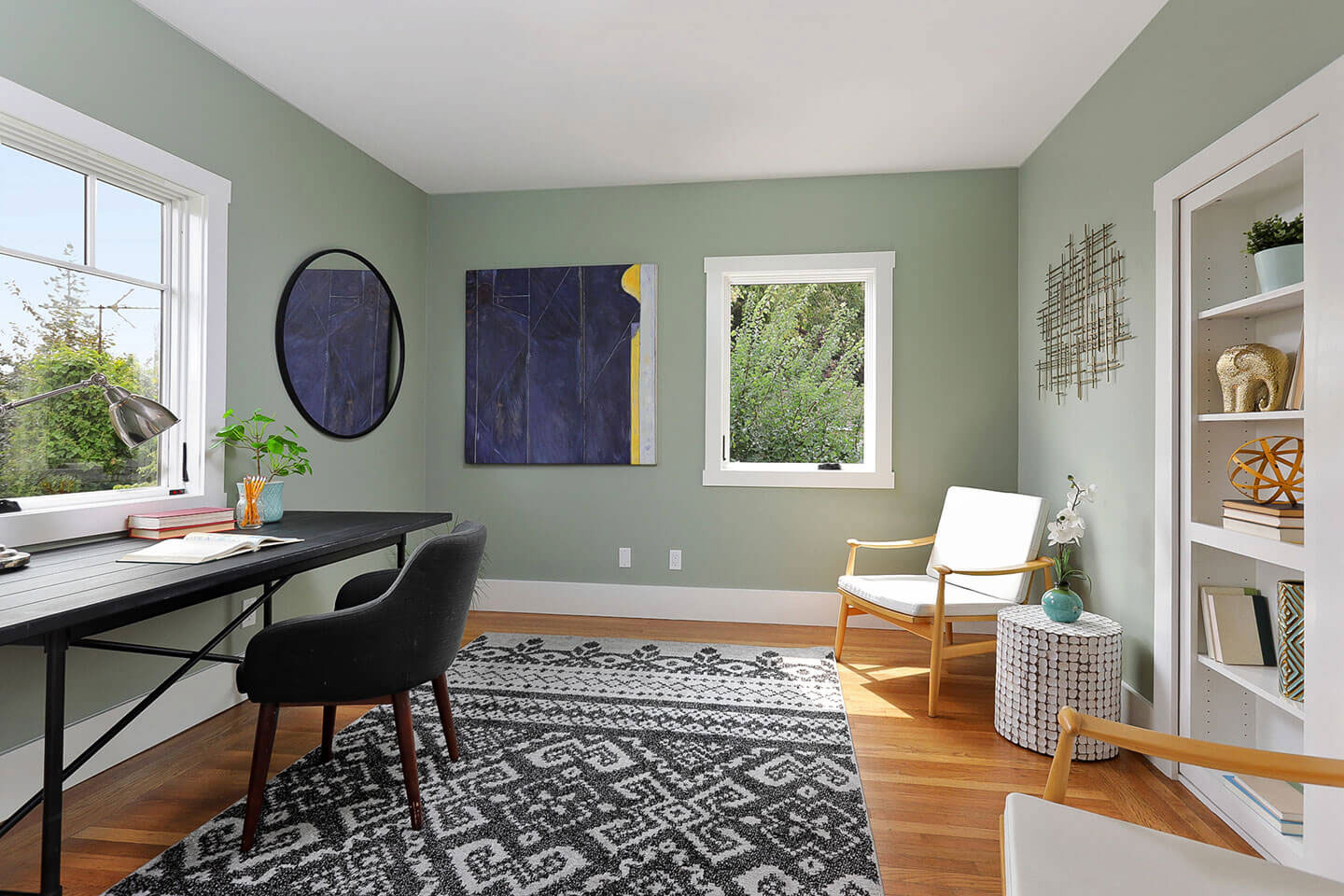 The image depicts a modern home office interior with a desk, chair, rug, window, and various decorative items.