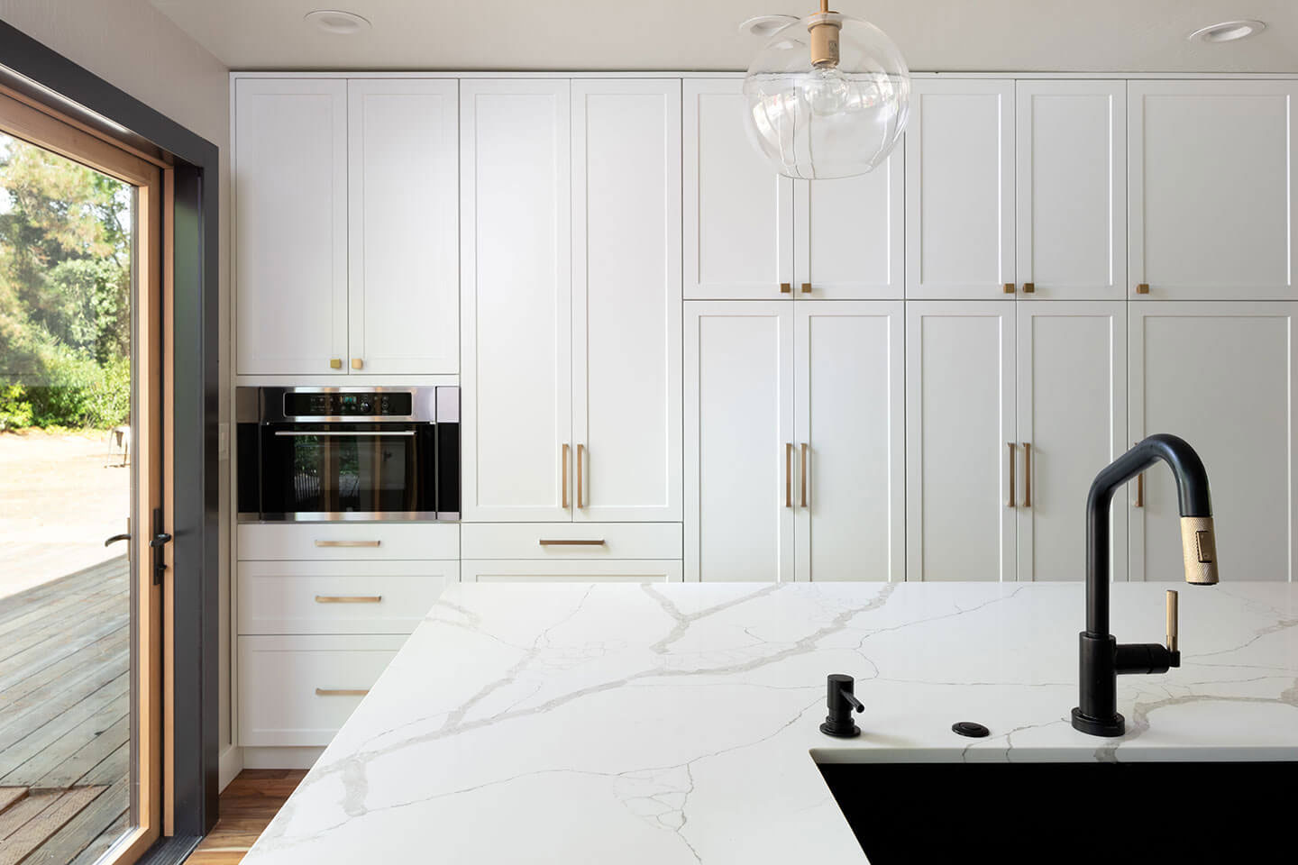 A modern kitchen with white cabinets, marble countertops, stainless steel appliances, and a center island.